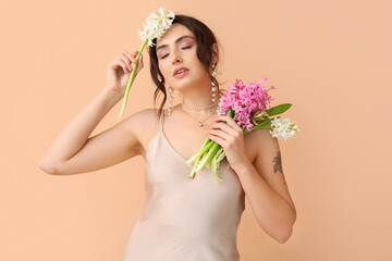 Pretty young woman with hyacinth flowers on color background