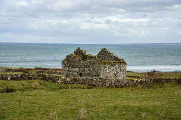 ruins of old church and graveyard Kilcummin Co. Mayo, Ireland with Atlantic Ocean on the background