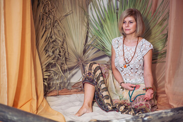Fototapeta premium The concept of zen, peace, balance. A woman sits and meditates using Mudra, keeping her legs crossed