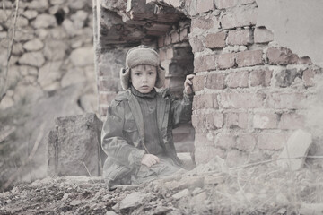 Child and  war. Poor, homeless child in the ruins of a destroyed house. 