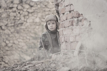 Child and  war. Poor, homeless child in the ruins of a destroyed house. 