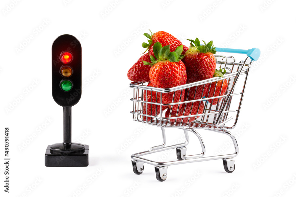 Poster Fresh strawberries in a cart and a miniature traffic light isolated on a white background