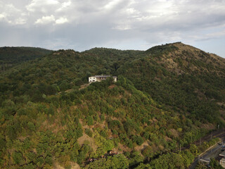 Mesmerizing view of the building on the top of the hill with dense greenery against a cloudy sky