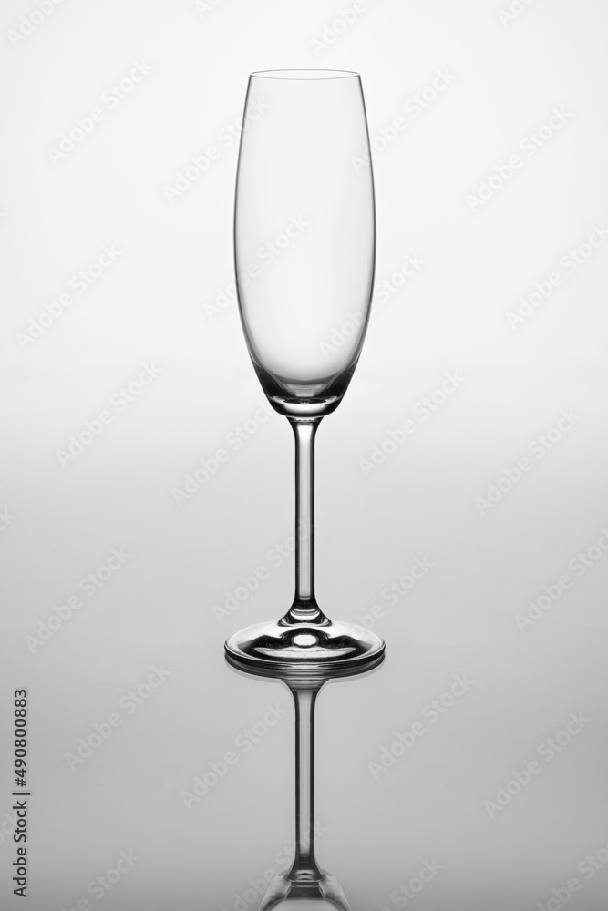 Sticker Vertical shot of a champagne glass with its reflection on a grey background