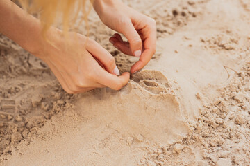 close up photo of woman hands sculpting vagina from white sand
