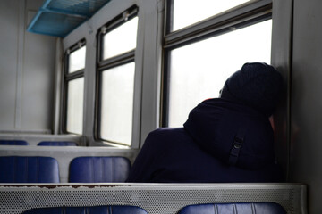 Lonely passenger sitting in the empty train with their head leaning onto the wall