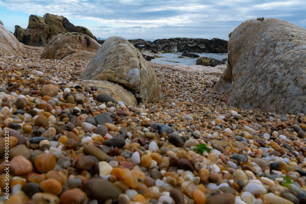 Poster scenic view of a beach with tiny rocks on cloudy sky background