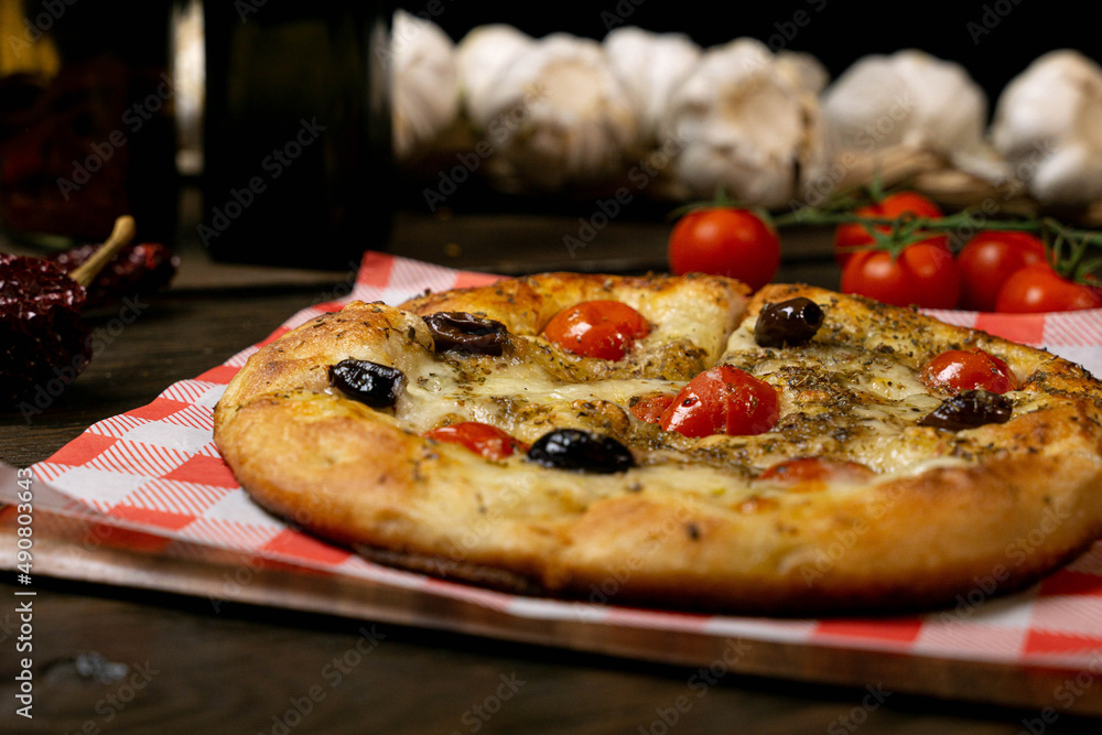 Canvas Prints Closeup shot of a focaccia bread with tomatoes and olives on a wooden table