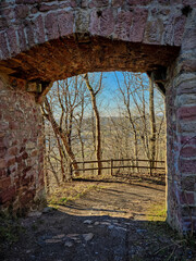 Bogen Tor einer mittelalterlichen Burgruine in der Rhön bei blauem Himmel und mit Wald im Winter