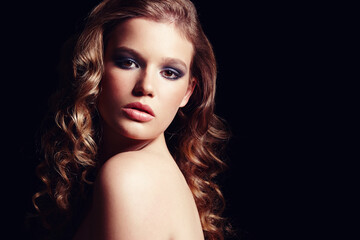 Fototapeta premium Luring you in with her sensual beauty. Studio portrait of a gorgeous brunette looking over her shoulder isolated on black.