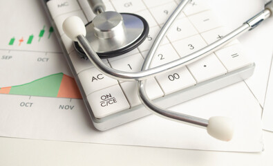 Medical practice financial analysis charts with stethoscope and calculator. Close up