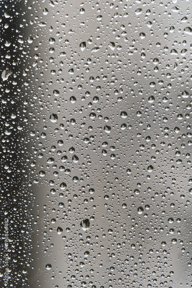 Poster closeup of a window glass covered with raindrops with blurred view in the background
