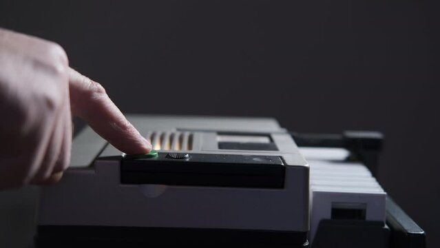 Hand of a man presses green button of a Slide magazine projector. Antique white slider projector working to project slide photographs and to create slideshow. Thin slides in a white plastic frame.
