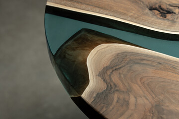 Obraz na płótnie Canvas Expensive vintage furniture. The table is covered with epoxy resin and varnished. Luxury quality wood processing. Wooden table on a dark background. A blue epoxy river in a round tree slab.
