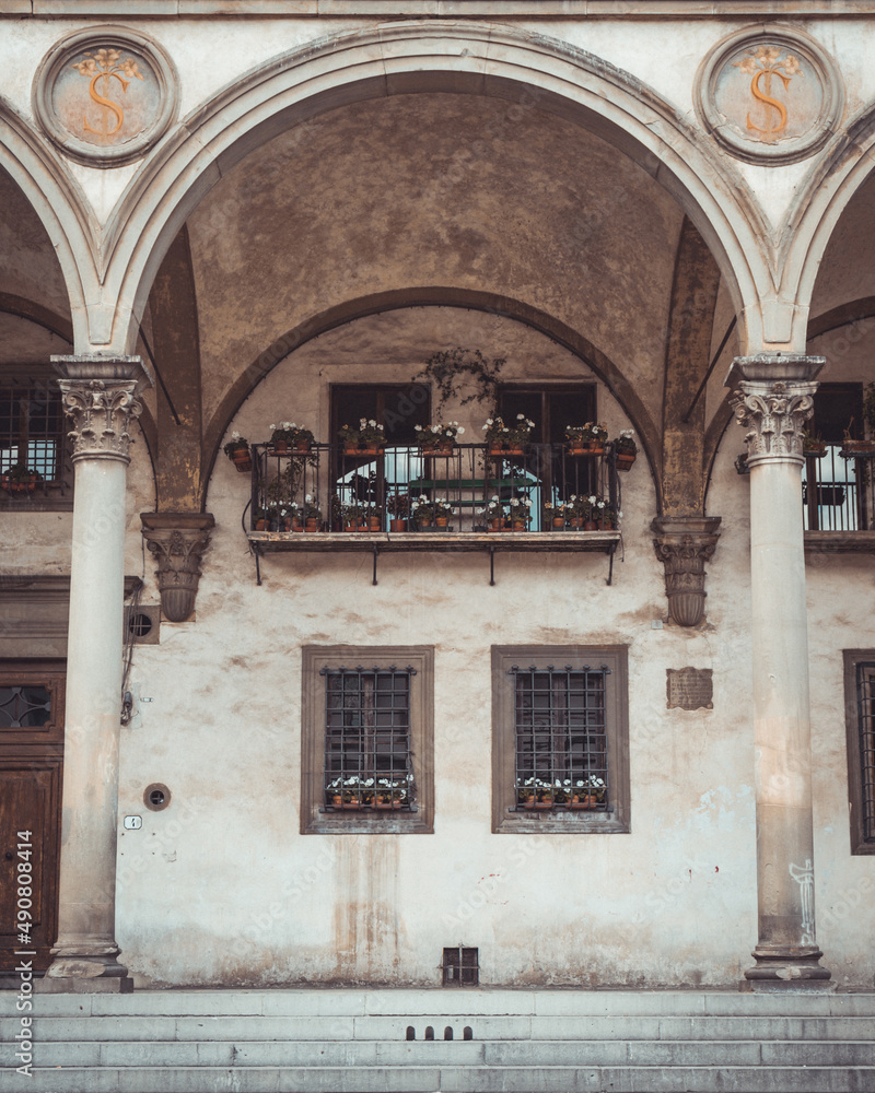 Poster view of the facade of an old building with flowers in pots on the window