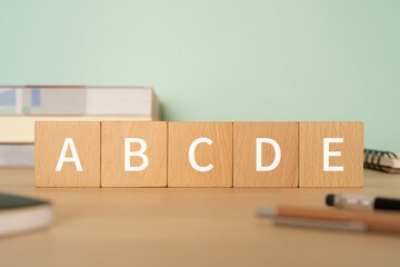 「ABCDE」と書かれた積み木、ペン、ノート、参考書