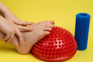 children's feet with a red balancer on a light yellow background, treatment and prevention of flat...