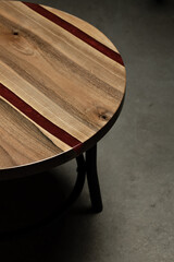 Expensive vintage furniture. The table is covered with epoxy resin and varnished. Luxury quality wood processing. Wooden table on a concrete background. A red epoxy river in a round tree slab.