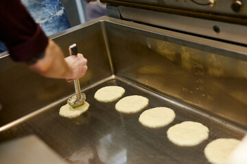 the chef is frying a large batch of pancakes