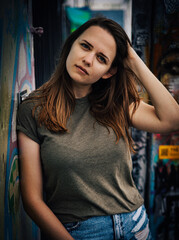 Young and beautiful woman leans against a colorful wall and poses for the camera - typical street style