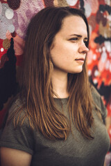 Young and beautiful woman leans against a colorful wall and poses for the camera - typical street style