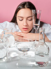 Portrait of a young brunette in refraction through glasses of water, face and pure water, concept