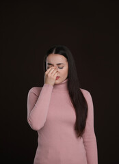 Young woman suffering from cold on dark background