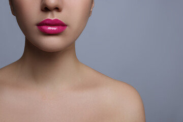 Closeup view of woman with beautiful full lips on grey background. Space for text