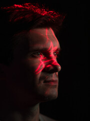 Modern technologies and human, concept. Portrait of a young man with a projection of red lines on his face, scanning or identification. Virtual Augmented Reality interfaces