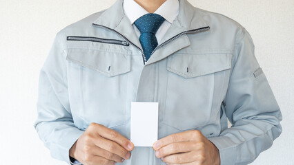 作業服の男性・建設業イメージ｜空白の名刺、ビジネスカードを持つ