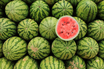 A sliced open watermelon on top of a watermelon background - obrazy, fototapety, plakaty