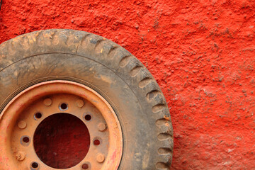 Fototapeta na wymiar Close up image of a wheel against a red wall background