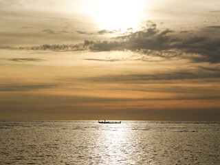 A silhouette of boat with sunset as background