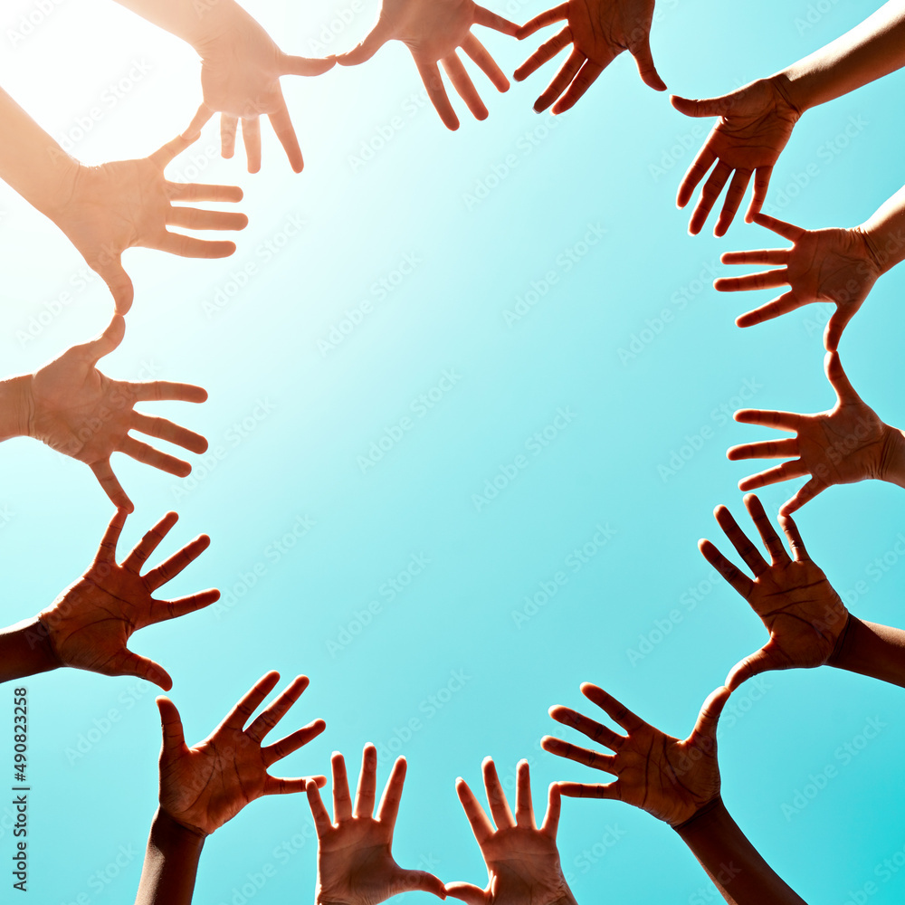 Poster we are one. cropped shot of a group of unidentifiable businesspeople joining their hands in a gestur