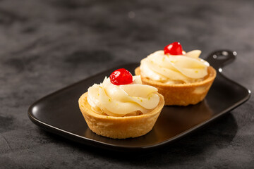 Lemon tartlets decorated with cherry.