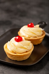 Lemon tartlets decorated with cherry.