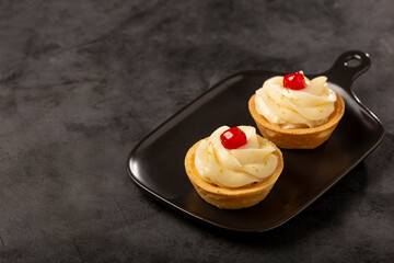 Lemon tartlets decorated with cherry.
