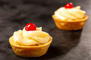 Lemon tartlets decorated with cherry.