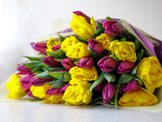 Bunch of yellow and purple tulip, bouquet of flowers for mothers day card, Easter or woman's day. Spring tulips on white background. Side view. Selective focus. Close up