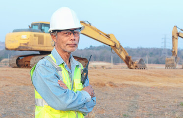 Portrait of an Asian male senior engineer wearing a vest and helmet inspects civil works, a...