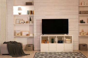 Modern TV on cabinet, ottoman and decor elements in living room