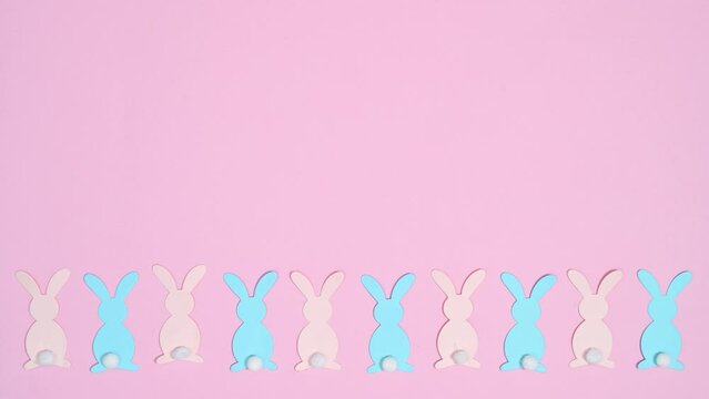 Pastel pink and blue rabbits move on bottom of bright pink background. Flat lay. copy space stop motion