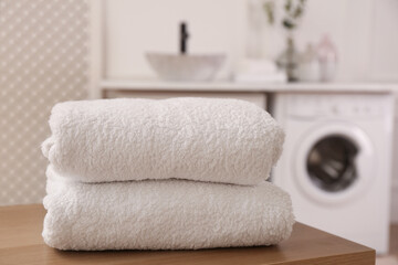 Fototapeta na wymiar Clean folded towels on wooden table in laundry room