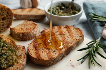 Pouring oil onto slice of toasted bread on board, closeup