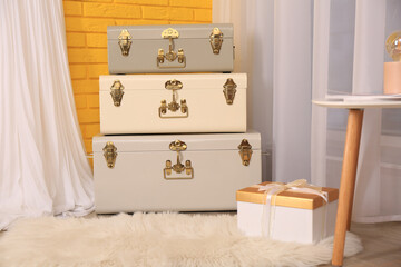 Fototapeta na wymiar Storage trunks and gift box near yellow brick wall indoors. Interior design
