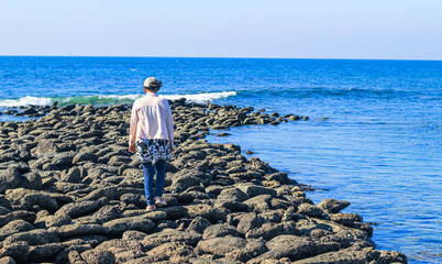 A tourist girl walking on giant's Causeway in St. Martin's Island, Bangladesh. Magical sunrise, clouds, and waves hitting the coast. Giant's Causeway looks like a jetty.