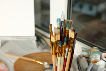 Many different paintbrushes near window, closeup view