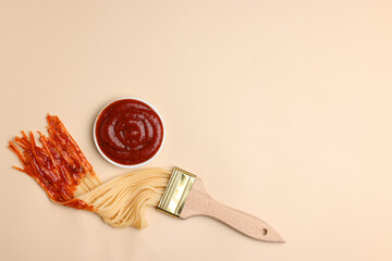 Brush painting with spaghetti dipped in ketchup on beige background, flat lay. Space for text....