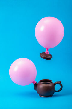 Two Pink Balloons On A Teapot On A Blue Background