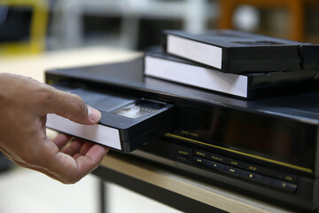 Close-up hand put or insert video cassette tape VHS old retro style on video record playback...